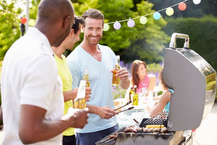 Männer am Grill mit Bier in der Hand