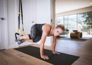 Sportlerin mit dem TRX im Wohnzimmer