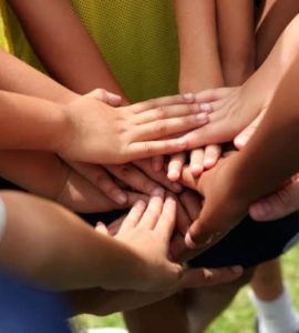 Hände die auf einem Huddle zusammen gelegt sind.