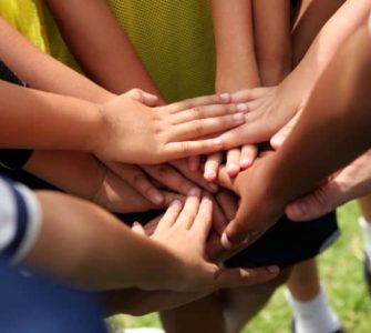 Hände die auf einem Huddle zusammen gelegt sind.
