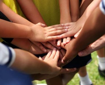 Hände die auf einem Huddle zusammen gelegt sind.