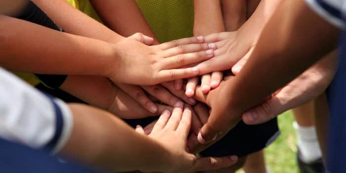 Hände die auf einem Huddle zusammen gelegt sind.