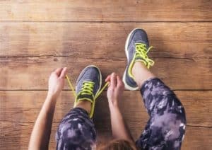 Sportlerin mit Muskelkater schnürt sich die Schuhe