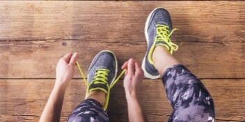 muskelkater training Sportlerin mit Muskelkater schnürt sich die Schuhe