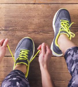 Sportlerin mit Muskelkater schnürt sich die Schuhe