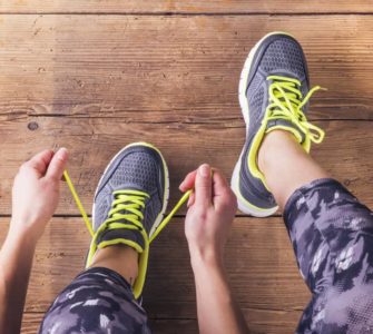 Sportlerin mit Muskelkater schnürt sich die Schuhe