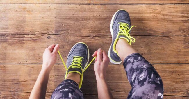 muskelkater training_big Sportlerin mit Muskelkater schnürt sich die Schuhe