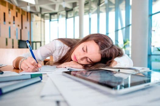 Frau, die auf dem Schreibtisch den Kopf abgelegt hat