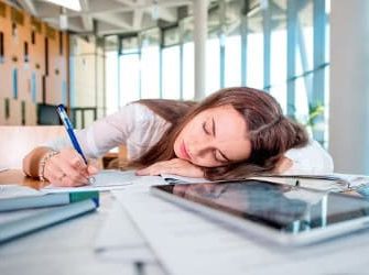 Frau schläft auf Schreibtisch