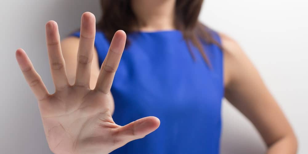 Nein Sagen Frau in blauem Kleid streckt die Hand nach vorne und sagt Nein