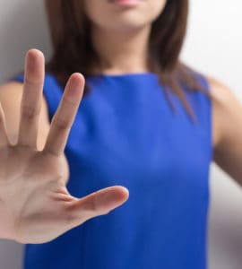 Frau in blauem Kleid streckt die Hand nach vorne und sagt Nein