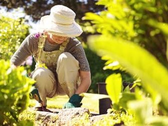 Frau arbeitet kniend im Garten