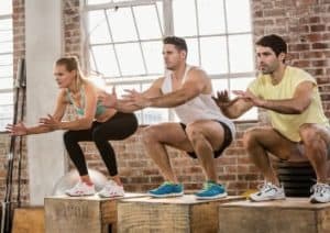 3 Sportler machen Jumping Squats