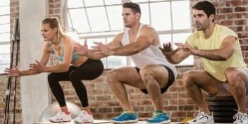 3 Sportler machen Jumping Squats