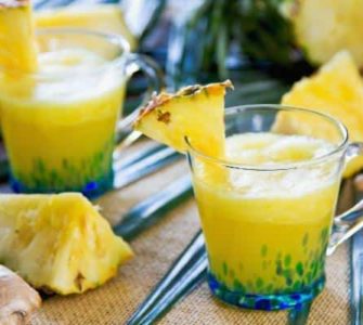 Ananas-Smoothie mit Ingwer in einem Glas, das mit 1/8 Ananasscheibe dekoriert wurde.