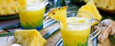 Ananas-Smoothie mit Ingwer in einem Glas, das mit 1/8 Ananasscheibe dekoriert wurde.