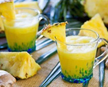 Ananas-Smoothie mit Ingwer in einem Glas, das mit 1/8 Ananasscheibe dekoriert wurde.