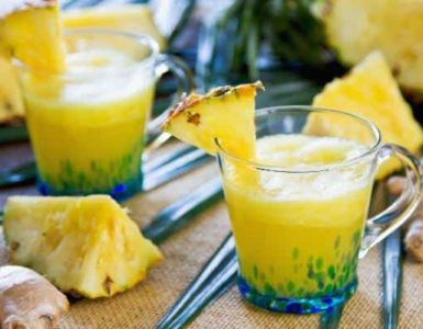 Ananas-Smoothie mit Ingwer in einem Glas, das mit 1/8 Ananasscheibe dekoriert wurde.