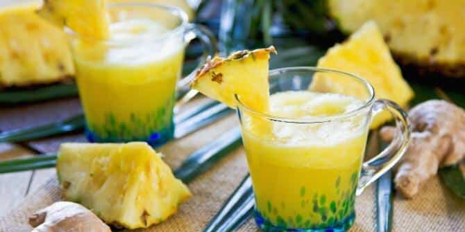 Ananas-Smoothie mit Ingwer in einem Glas, das mit 1/8 Ananasscheibe dekoriert wurde.