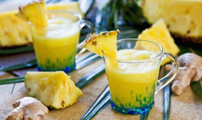 Ananas-Smoothie mit Ingwer in einem Glas, das mit 1/8 Ananasscheibe dekoriert wurde.