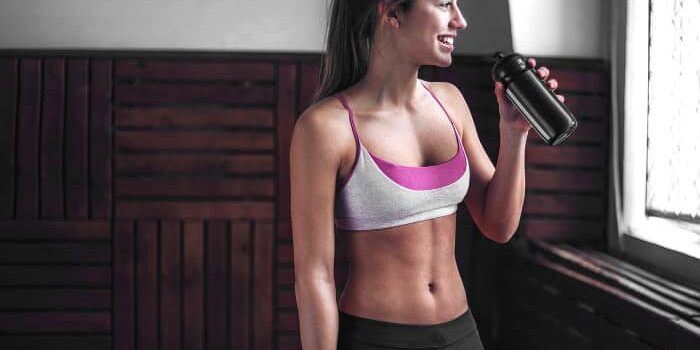 schlank Frau in Sportkleidung trinkt aus einer Flasche nach dem Fitnesstraining