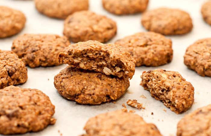 Nuss-Haferflocken-Schokocookies auf einem Backblech mit weißem Backpapier