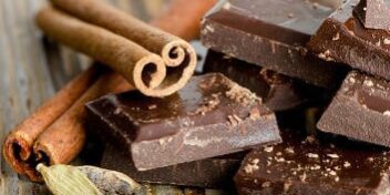 Stücken dunkler Schokolade nebst zweier Zimtstangen