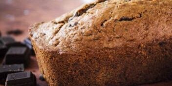 schokoladen-zucchini-kuchen_353 Ein Schokoladen-Zucchini-Kuchen mit danebenliegender Zucchini sowie Stücken dunkler Schokolade