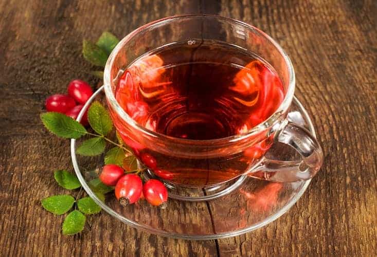 Hagebutten Tee in Glastasse auf Holztisch