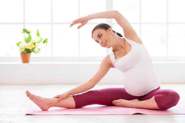 schwangere frau macht yoga seitbeuge