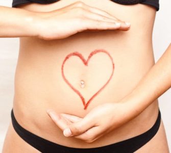 Bauch einer Frau mit rotem Stift wurde ein Herz um den Bauchnabel gezeichnet. Thema: Darm - Ursache für Übergewicht