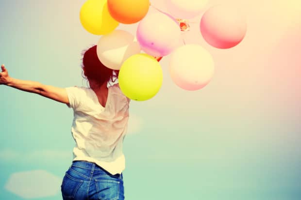 Junge Frau mit bunten Luftballons ist glücklich