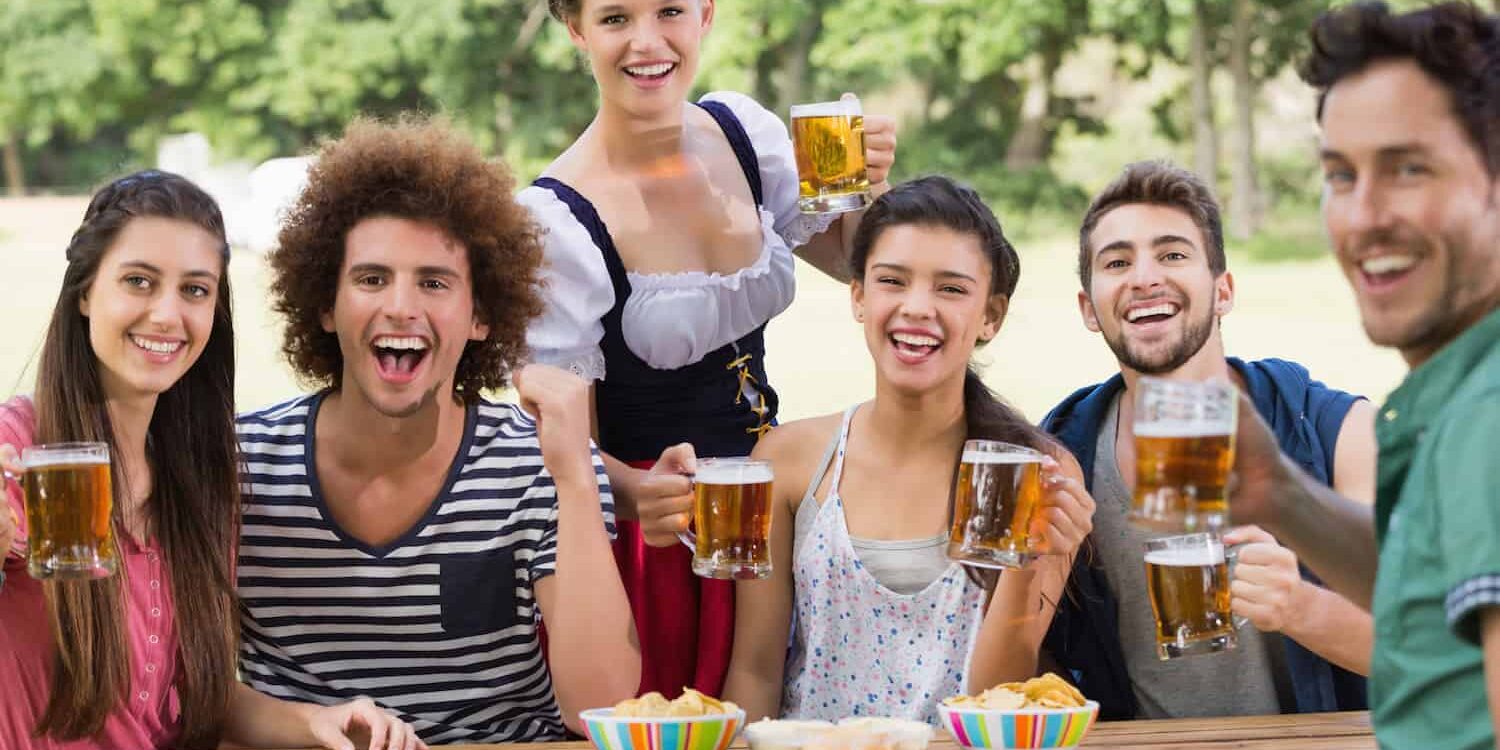 Oktoberfest: Fit & gesund auf der Wiesn Gruppe junger Menschen sitzen an einem Holztisch und trinken Bier auf dem Oktoberfest