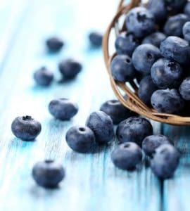 heidelbeeren in korb auf hellblauem tisch