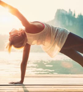 Junge Frau macht Yoga am See und fühlt sich wohl