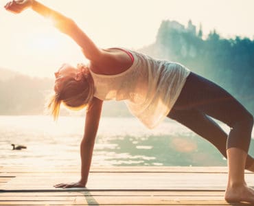 Junge Frau macht Yoga am See und fühlt sich wohl
