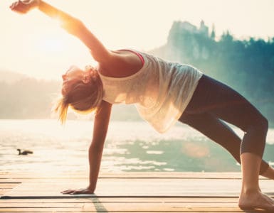 Junge Frau macht Yoga am See und fühlt sich wohl