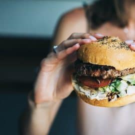 Frau hat Hunger und hält Burger in den Händen