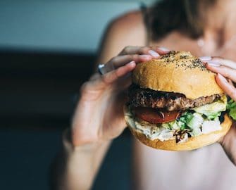 Frau hat Hunger und hält Burger in den Händen