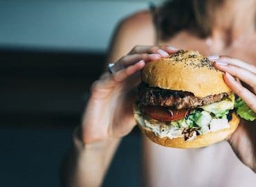 Frau hat Hunger und hält Burger in den Händen