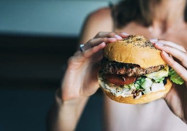 Frau hat Hunger und hält Burger in den Händen