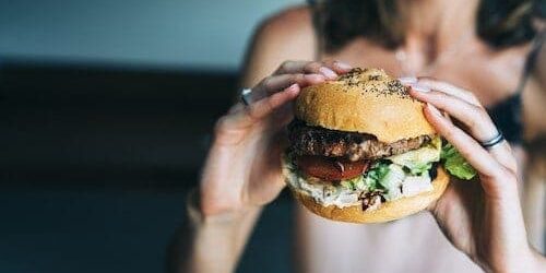 Burger Cheat Day Frau hat Hunger und hält Burger in den Händen