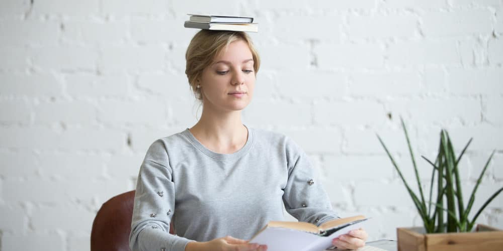 shutterstock_499599217 Frau sitzt gerade mit einem Buch auf dem Kopf bei der Arbeit