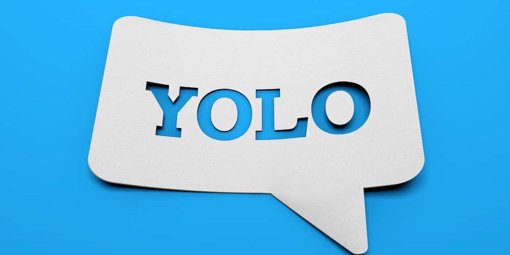 Yolo weißes schild mit YOLO in sprechblasenform vor blauem Hintergrund