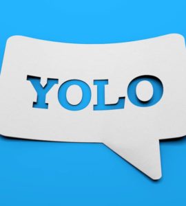 weißes schild mit YOLO in sprechblasenform vor blauem Hintergrund