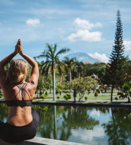 Junge Frau sitzt im Lotussitz und macht Yoga auf bali