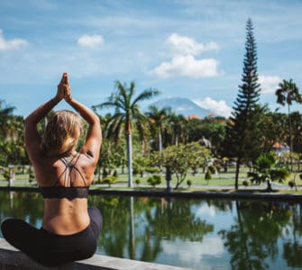 Junge Frau sitzt im Lotussitz und macht Yoga auf bali