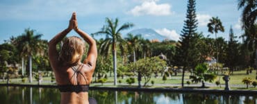 Junge Frau sitzt im Lotussitz und macht Yoga auf bali