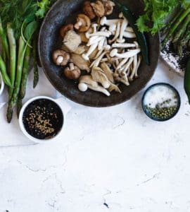 Tisch gedeckt mit Tellern voller gesunder, vegetarischer und veganer Lebensmitteln. Pilze, Sojabohnen, Gemüse