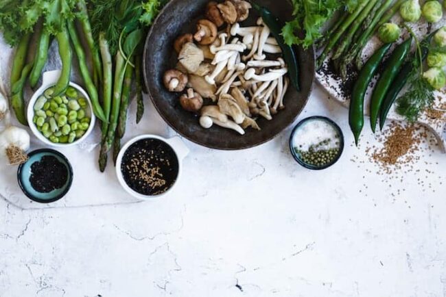 Tisch gedeckt mit Tellern voller gesunder, vegetarischer und veganer Lebensmitteln. Pilze, Sojabohnen, Gemüse